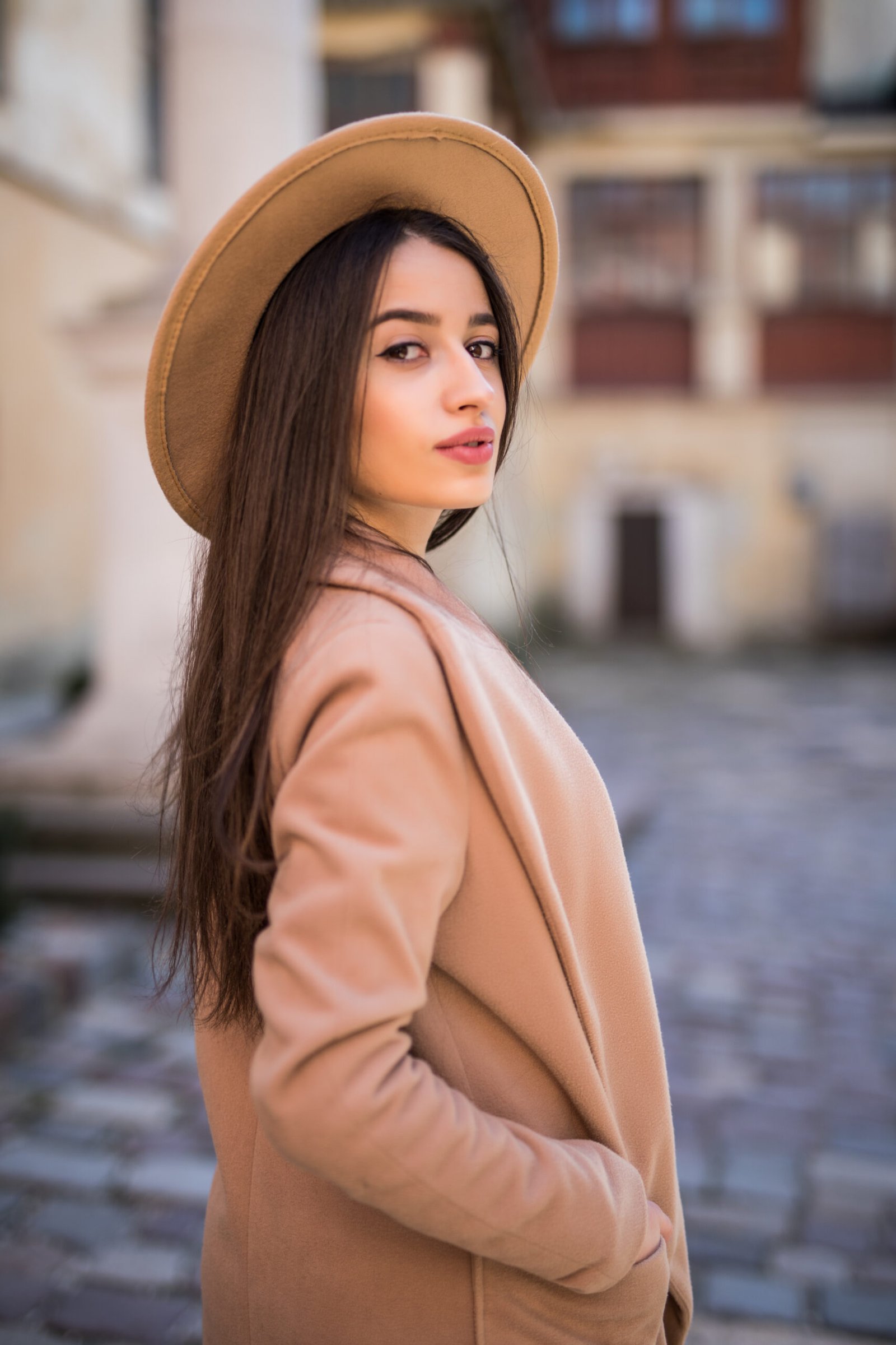tender smiling lady is walking on the street and posing in casual modern coat and hat