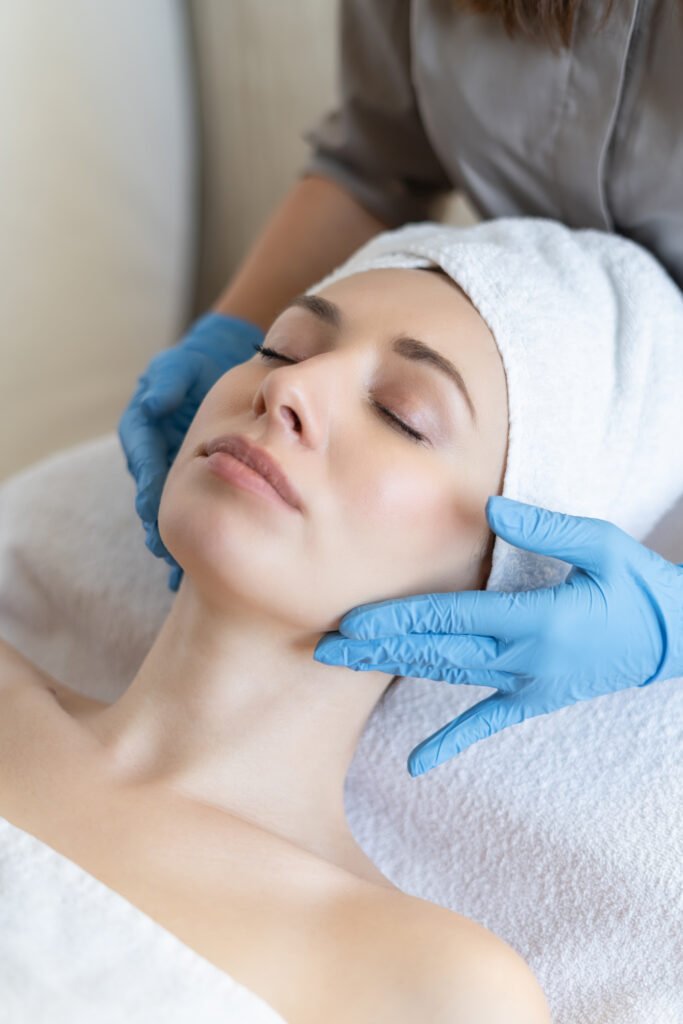 a young beautiful girl lies on the table at the beautician and receives procedures, a light massage, hands in blue gloves, the skin is smooth